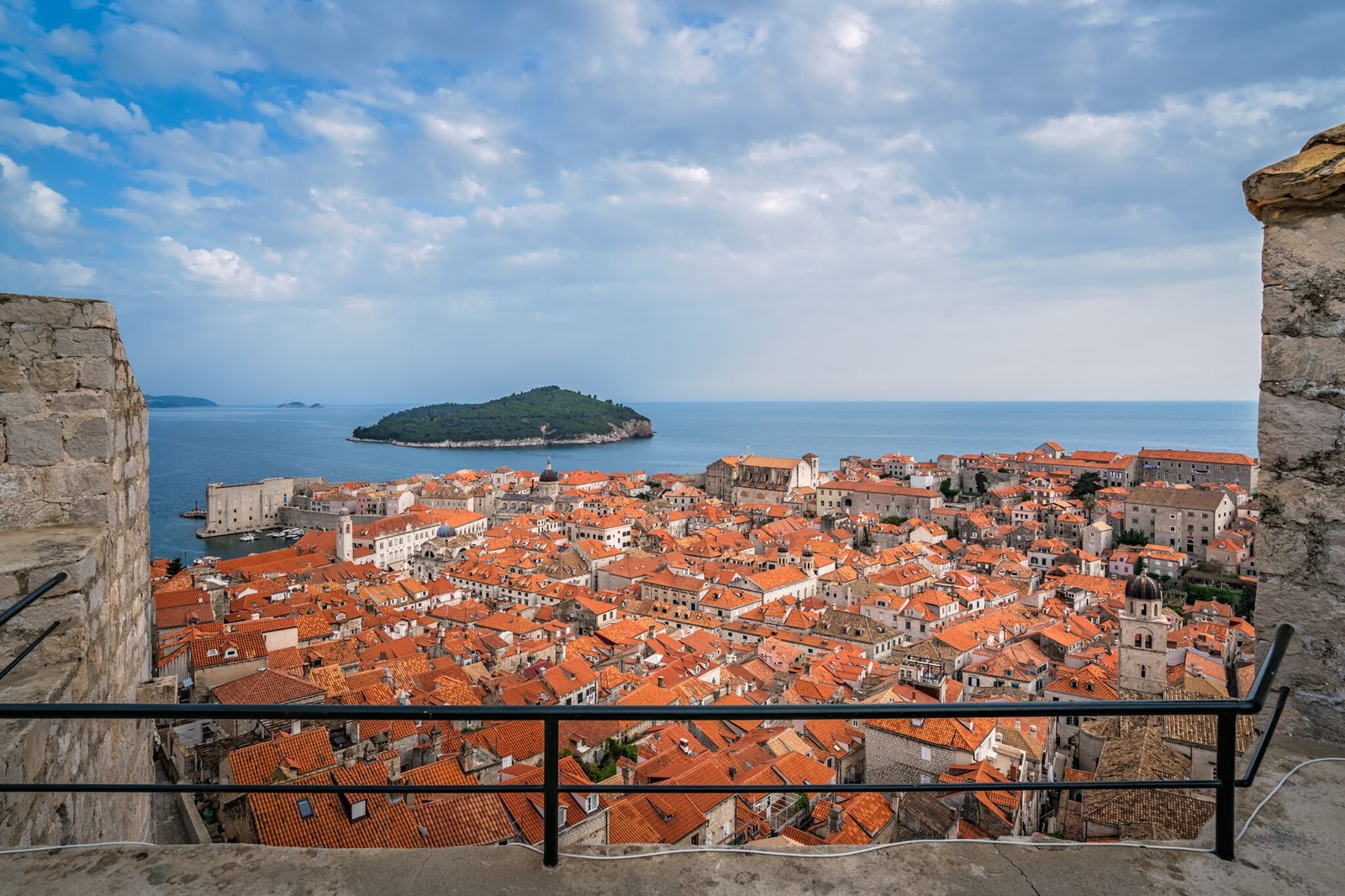 Rooftops of old houses in Dubrovnik, viewed from the Old Town fortified walls with Lokrum Island in the background