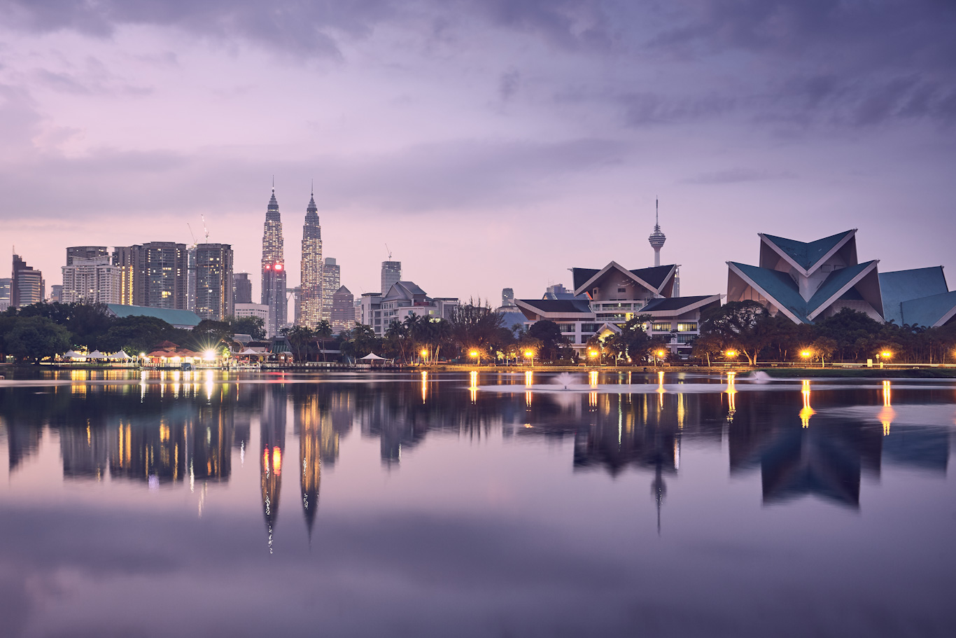 Moody sunrise in Kuala Lumpur in Malaysia. Reflection of the urban skyline in the lake.
