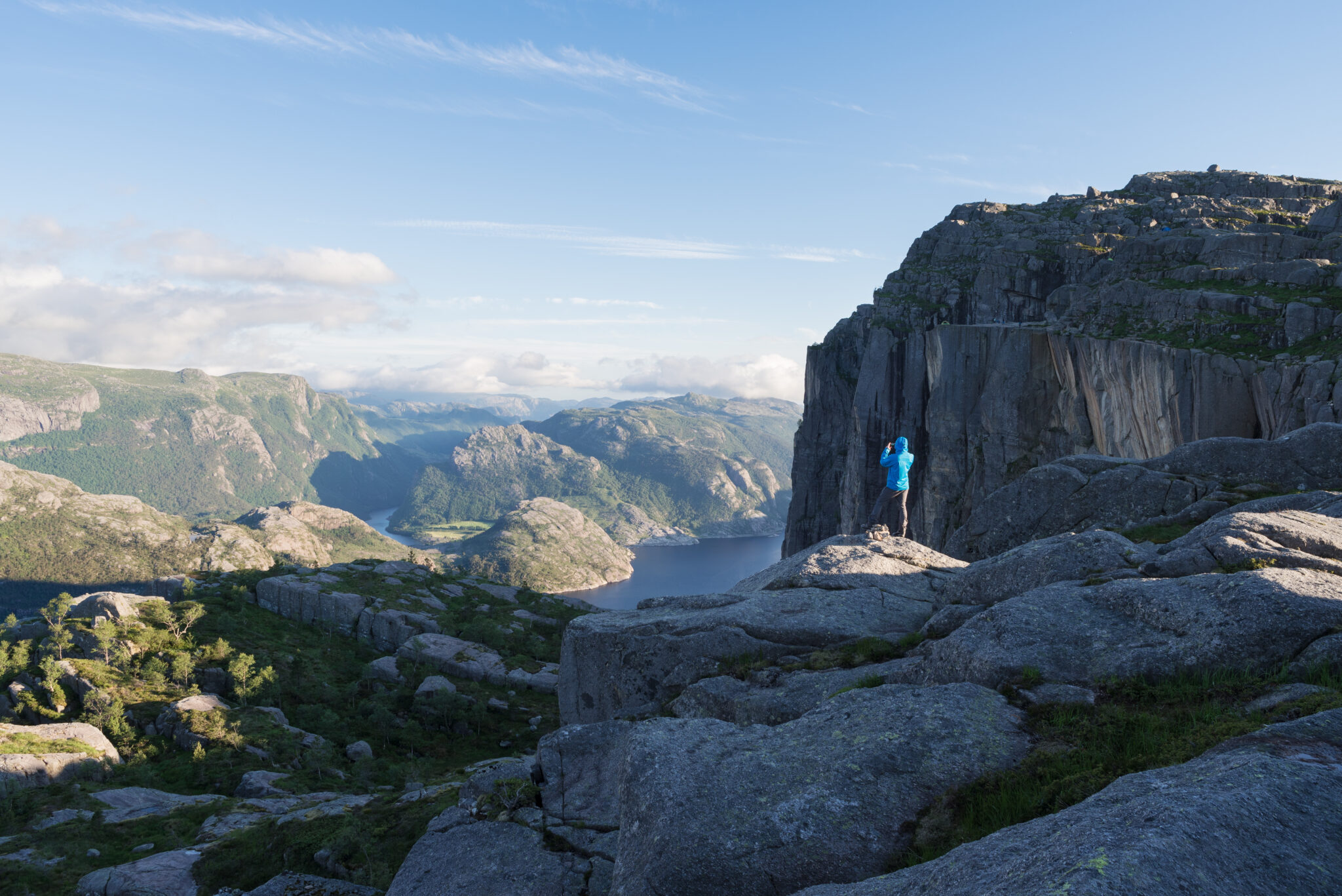 Near Preikestolen (Pulpit Rock), the famous tourist attraction in Ryfylke, towers over the Lysefjord. Guy on the rock takes pictures of nature on the phone